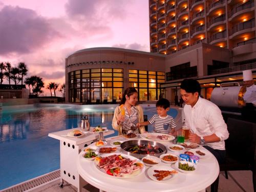 a family is sitting at a table with food at Loisir Spa Tower Naha in Naha