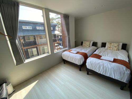 1 dormitorio con 2 camas y ventana grande en Neverland Chalet en Hakuba
