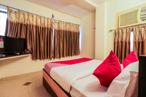een slaapkamer met een bed met rode kussens en een televisie bij Parnasala Princely in Rājahmundry