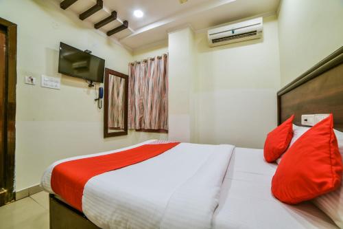 - une chambre avec un lit doté d'oreillers rouges et une télévision dans l'établissement OYO Surya Teja Residency, à Khammam