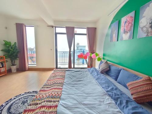 a bedroom with a large bed with a green wall at Sa Mộc House Tam Đảo - Venuestay in Vĩnh Phúc