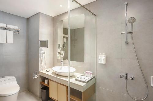 a bathroom with a shower and a sink and a toilet at Swiss-Belinn Luwuk in Luwuk