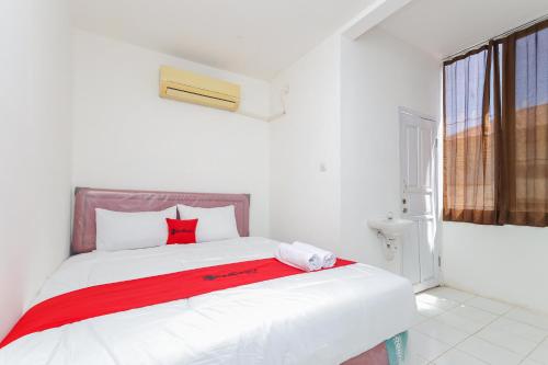 1 dormitorio con cama blanca y almohadas rojas en RedDoorz near Pasar Lama Serang en Serang