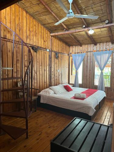 1 dormitorio con 1 cama en una habitación con paredes de madera en Hotel Pacande B&B en Alajuela