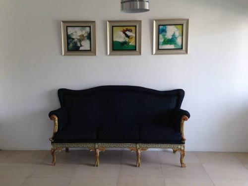 a black couch against a white wall with three pictures at Fortuna Beach in Flic-en-Flac