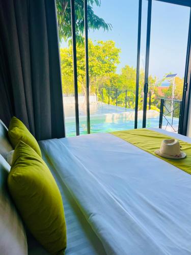 a bed with a yellow pillow and a hat on it at Pahili Pool Villas Koh Tao - SHA Plus in Koh Tao