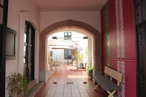 a hallway with an archway and a bench in a building at Hotel La Casa de María in Oaxaca City