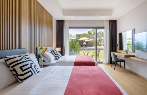 a bedroom with two beds and a desk and a balcony at The Grand Sumorum in Seogwipo