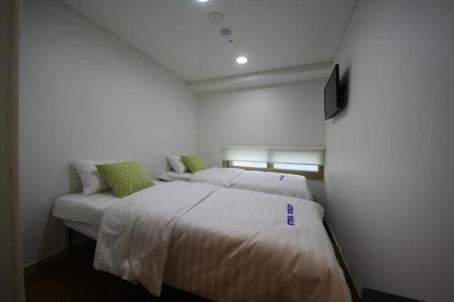 a bedroom with two beds and a tv on the wall at Star Guest House in Seoul