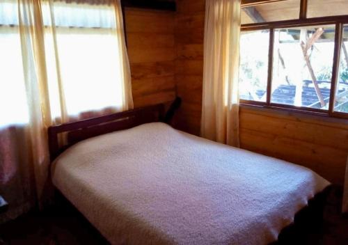 ein kleines Schlafzimmer mit einem Bett und einem Fenster in der Unterkunft Cozy cabin Casa Enya in Sibundoy