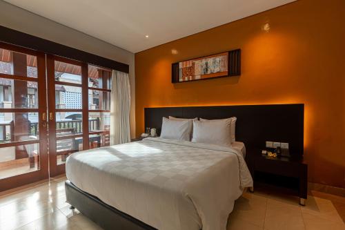 1 dormitorio con 1 cama grande y pared de color naranja en Fourteen Roses Beach Hotel, en Legian
