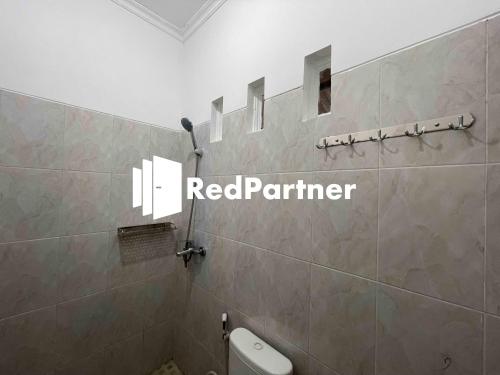 La salle de bains est pourvue de toilettes et d'un panneau rouge partenaire sur le mur. dans l'établissement Hotel Pusponjolo Syariah Semarang Mitra RedDoorz, à Semarang