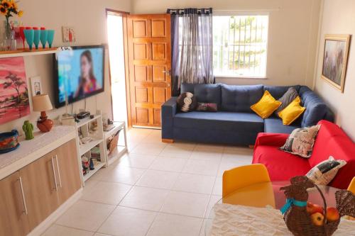 a living room with a blue couch and a tv at Casa de andar a 200m da areia Praia da Caueira SE in Praia Da Caueira