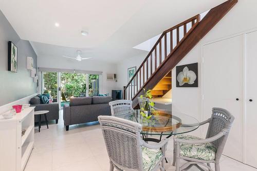 een eetkamer en een woonkamer met een glazen tafel en stoelen bij Lovely Spacious 2 Bedroom 2 Bathroom Townhouse in Resort in Port Douglas