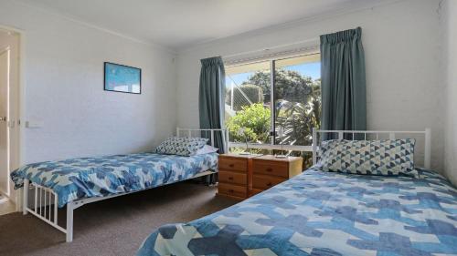 1 Schlafzimmer mit 2 Betten und einem Fenster in der Unterkunft Unit 3 18 Surf Circle Tura Beach in Tura Beach