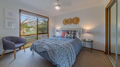 een slaapkamer met een bed, een raam en een stoel bij Florida Tree's in Inverloch