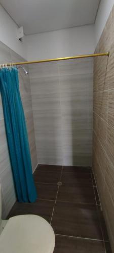 a bathroom with a toilet and a blue shower curtain at QUINTA RANCHO SANTIAGO CAMPESTRE capacidad 50 huéspedes in Riverita
