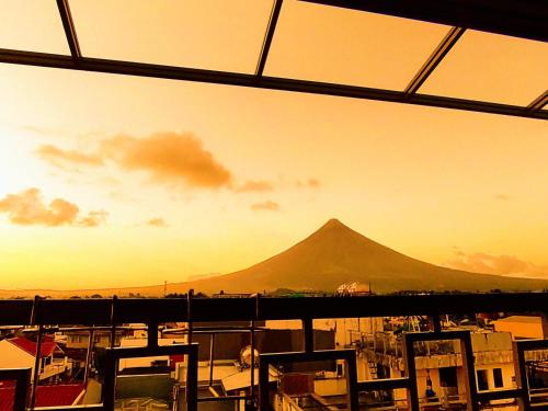 una montaña en la distancia con una puesta de sol en el fondo en The Panorama Penthouse Daraga, en Locsin