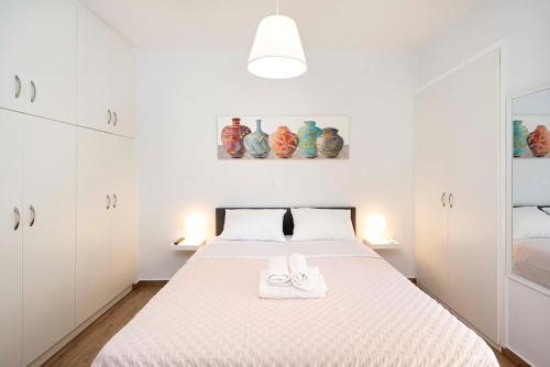 a white bedroom with a bed with two towels on it at Filoxenia MG city center in Athens