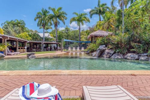 una persona sentada en una silla junto a una piscina en Lovely Spacious 2 Bedroom 2 Bathroom Townhouse in Resort en Port Douglas