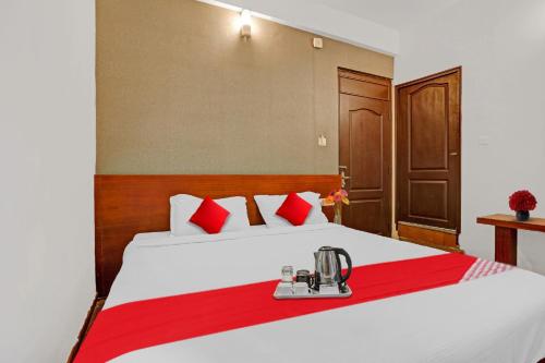sypialnia z dużym białym łóżkiem z czerwonymi akcentami w obiekcie OYO Hotel Jayam Ooty Residency w mieście Utakamand