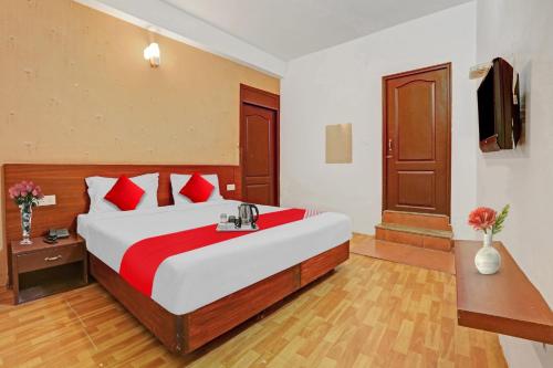 a bedroom with a large bed with red pillows at OYO Hotel Jayam Ooty Residency in Ooty