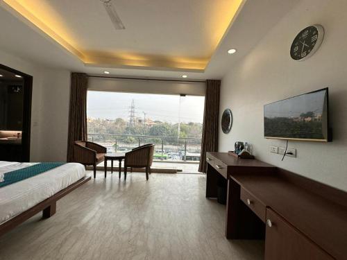 a hotel room with a bed and a table and a large window at Hotel The Imperio in New Delhi
