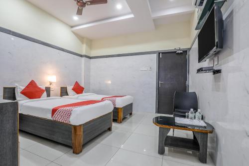 a bedroom with two beds and a tv and a chair at Hotel Src Grand in Vijayawāda