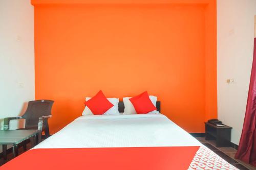 a bedroom with an orange wall and a bed with red pillows at Flagship New Cresent Park in Irugūr