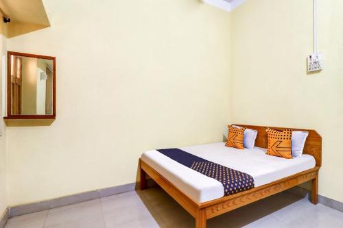 een klein bed in een kamer met een spiegel bij OYO Shivaye Rest House in Deoghar