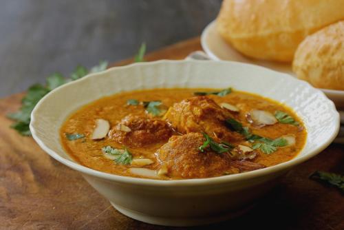 a bowl of soup on a table with a plate of bread at Hotel O Shivaye Rest House in Deoghar