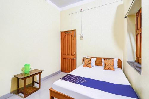 een slaapkamer met een bed en een kleine tafel bij OYO Shivaye Rest House in Deoghar