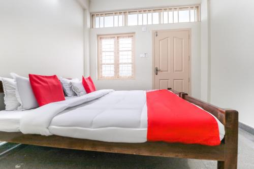 a bedroom with a large bed with red and white pillows at Appas Residency in Ambalavayal