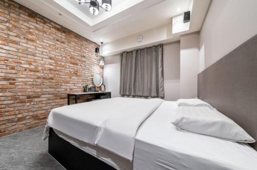 a bedroom with a large white bed with a brick wall at 27 Hotel in Anyang