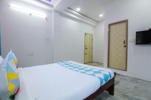 a white bedroom with a bed and a television at OYO Home Dk Homes in Maula Ali