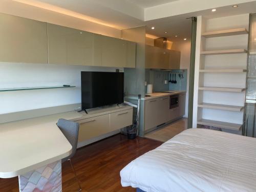 a bedroom with a bed and a tv and a kitchen at Beijing Elegant Seasons Park Apartment in Beijing