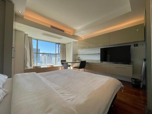 um quarto com uma cama grande e uma televisão de ecrã plano em Beijing Elegant Seasons Park Apartment em Pequim