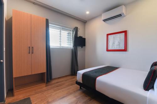 a bedroom with a bed and a cabinet and a window at Townhouse Spruce Hotels Bellandur in Bangalore