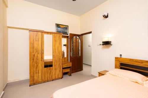 a bedroom with a bed and a wooden cabinet at Paradise Inn in Cochin