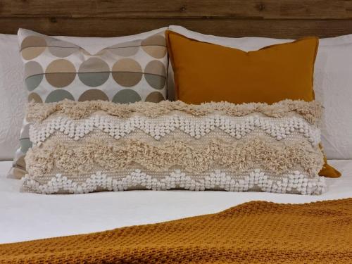 Una cama con almohadas naranjas y blancas. en Brushwood Studio, en Denmark