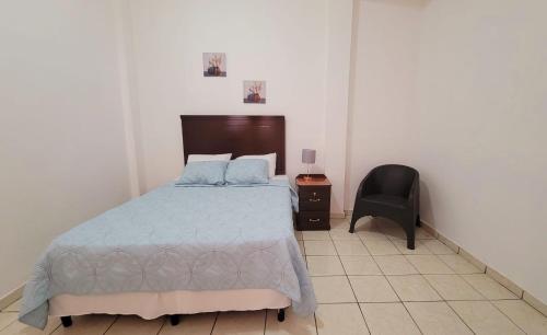 1 dormitorio con 1 cama y 1 silla en Casa en el Centro de Ilobasco, en Nanastepeque