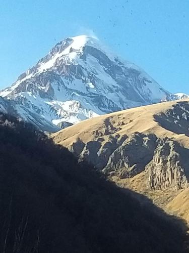 a snow covered mountain in the middle of a field at Emotion Kazbegi in Stepantsminda