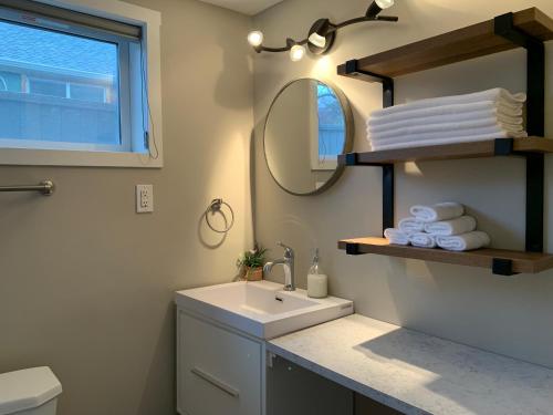 een badkamer met een wastafel en een spiegel bij Cheerful home close to downtown Kelowna in Kelowna