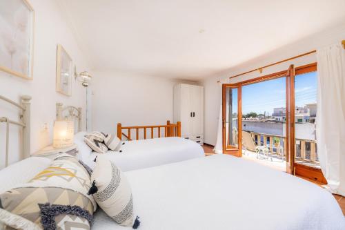 a bedroom with two beds and a balcony at Casa Can Pinyol in Cala Figuera