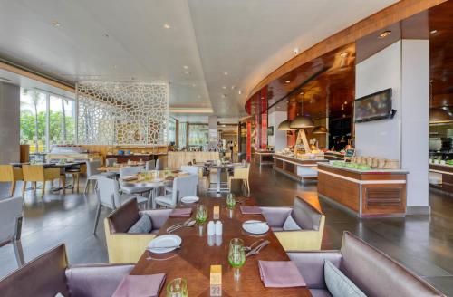 a restaurant with tables and chairs and a bar at Novotel Bengaluru Outer Ring Road in Bengaluru