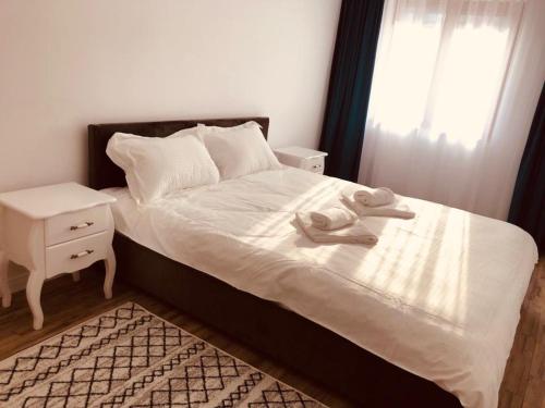 - une chambre avec un lit blanc, une table de chevet et une fenêtre dans l'établissement NARCISA, à Piatra Neamţ