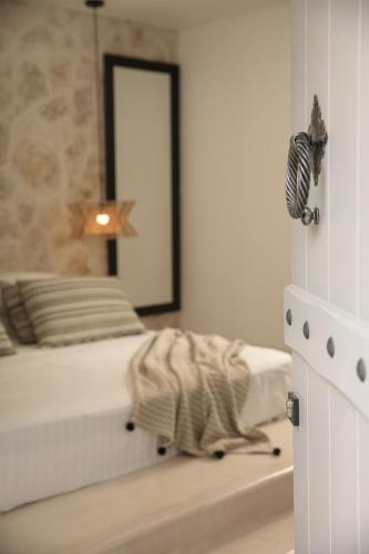 a white bedroom with a bed and a mirror at Naxos green Village hotel in Naxos Chora