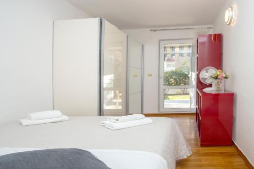 a white bedroom with a red dresser and a bed at Deluxe apartment Lea with large garden in Split