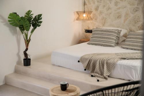 a bedroom with a white bed and a potted plant at Naxos green Village hotel in Naxos Chora