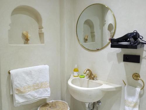 W białej łazience znajduje się umywalka i lustro. w obiekcie Serenehouse w Marakeszu